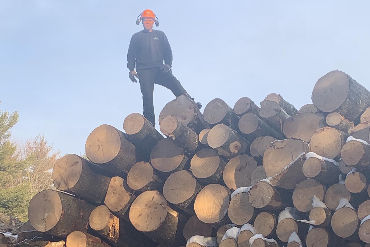 Quick break for a picture Adam Allen owner posing on pine sawlog pile